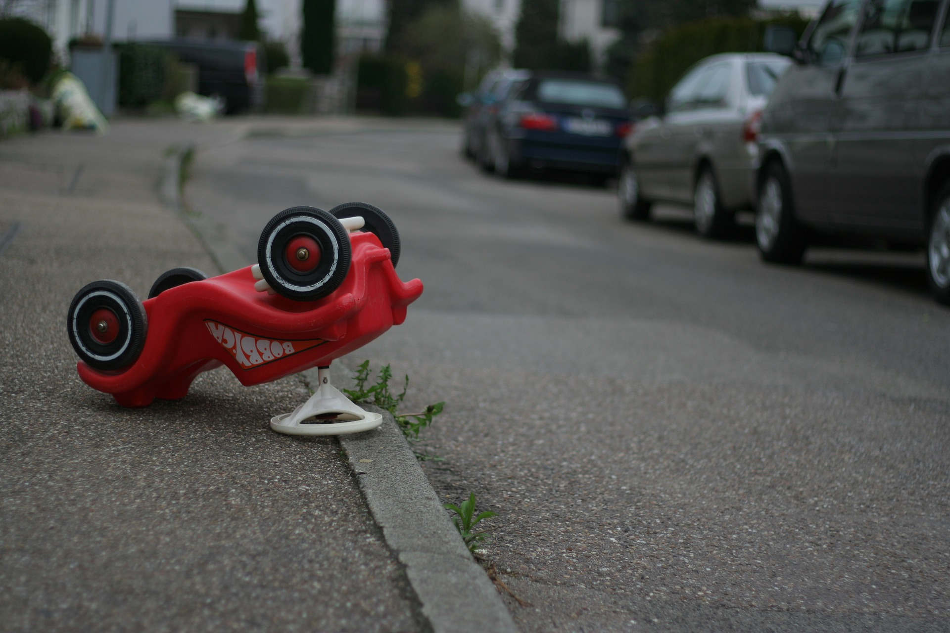 Red toy car flipped on curb